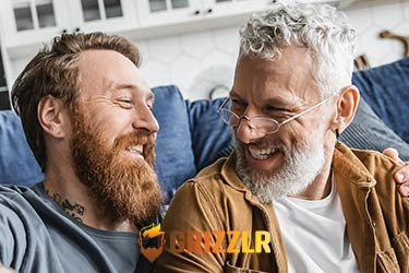 Two bearded gay bears laughing together on the sofa