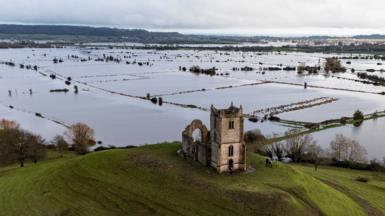 An aerial photo showing a sea of flooded fields in Somerset and in the foreground is a hill with a church on the top