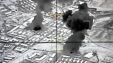 Black and white image of smoke rising from city.