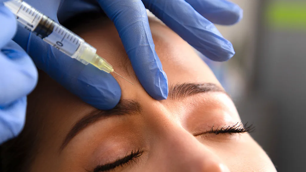 A close-up of a woman's face about to receive an injection