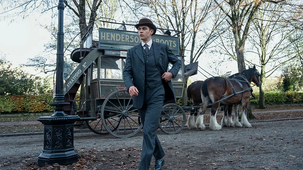 A still from Young Sherlock, showing a man in a suit in front of a horse and cart