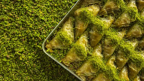 A tray of pistachio baklava over a bed of pistachios (Credit: Getty Images)