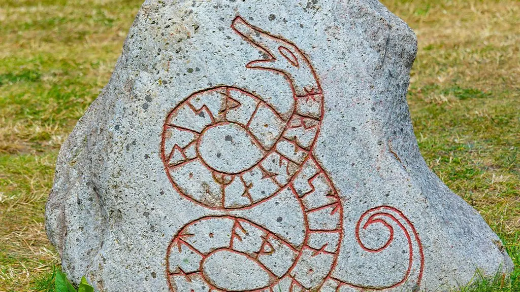 A triangular shaped stone covered in carvings including runic writing in a field (Credit: Matilda Welin)