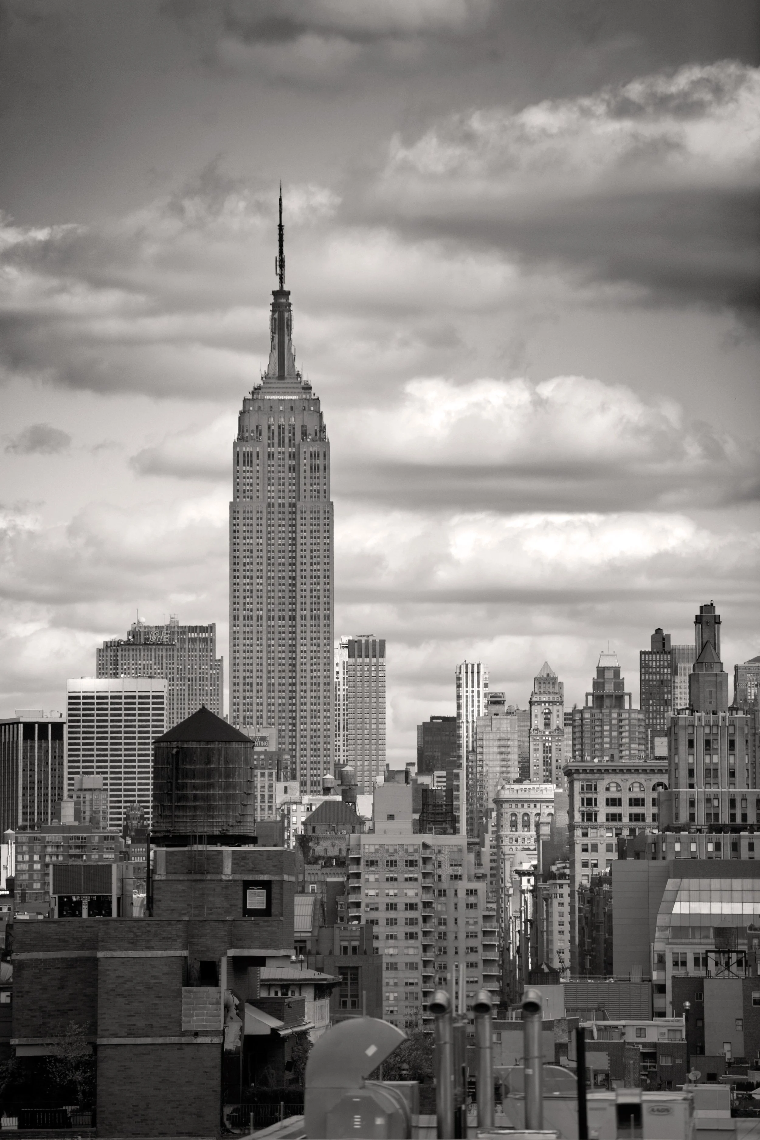 Black and white photo of the New York City skyline featuring the Empire State Building with cloudy skies.