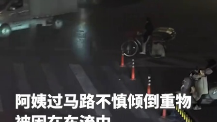 阿姨过马路不慎倾倒重物被困车流中 女司机下车小跑上前将她扶起