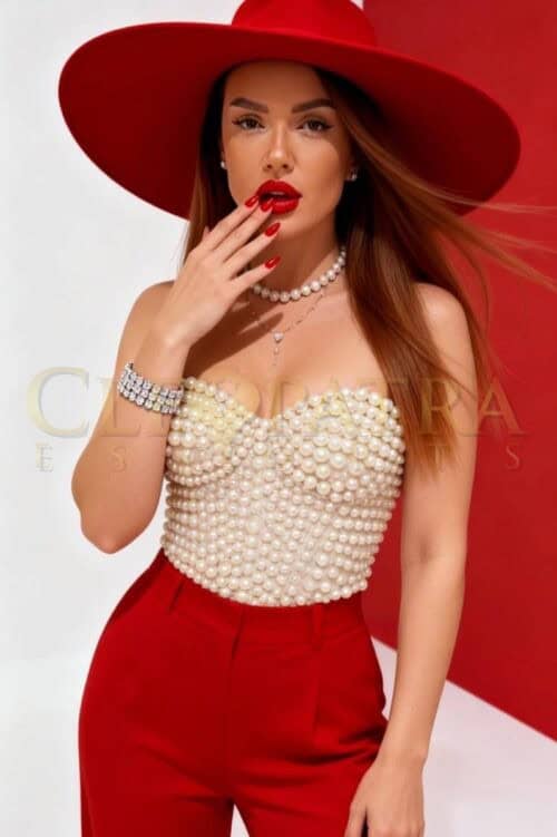 Elegant woman in red hat and pearl top in London.