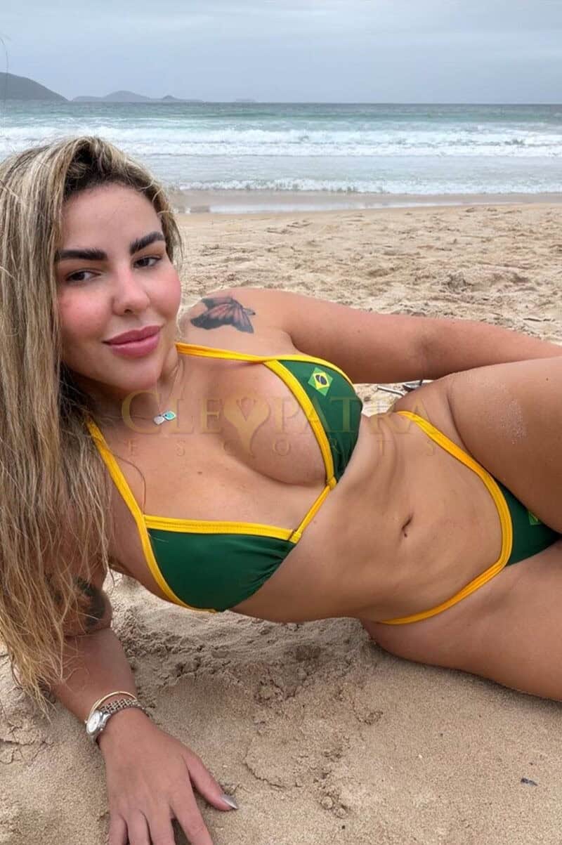 Seductive woman in Brazilian flag bikini relaxing on the beach.
