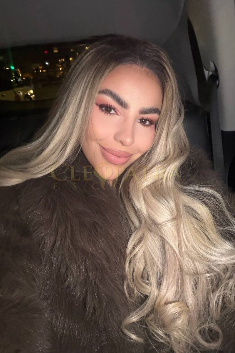 Elegant London escort woman with blonde hair and makeup.