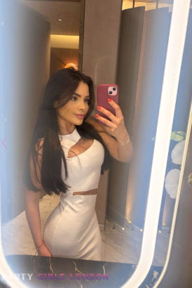 Slim young brunette in a white dress taking a selfie